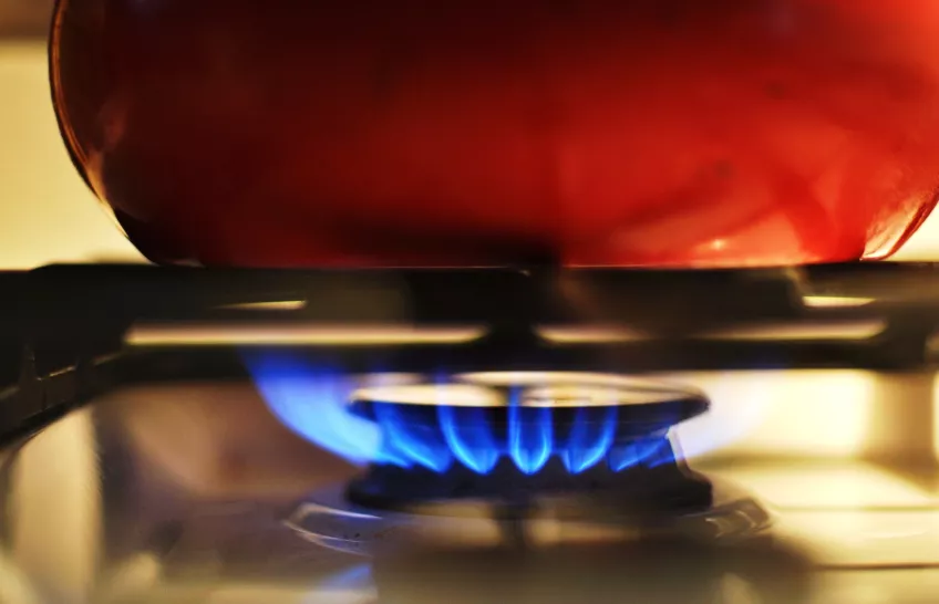 A gas stove and a saucepan, with a blue flame. Photo.